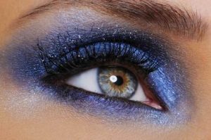 one female eye with bright blue eyeshadow - macro shoot