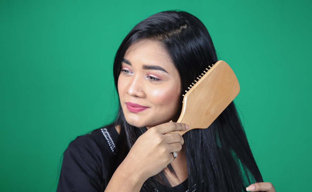 প্যাডেল ব্রাশ (Paddle Brush) এর ব্যবহার দেখাচ্ছে একজন 